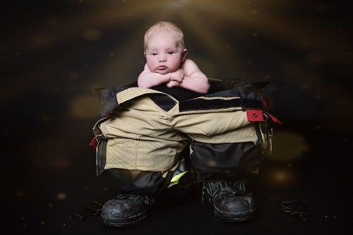 Fotoshooting mit Baby in Düsseldorf, das auf einer Feuerwehrausrüstung posiert